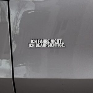 Sticker „Ich fahre nicht. Ich beaufsichtige.“ links auf der Heckklappe eines Model Y Juniper, neben dem Rücklicht