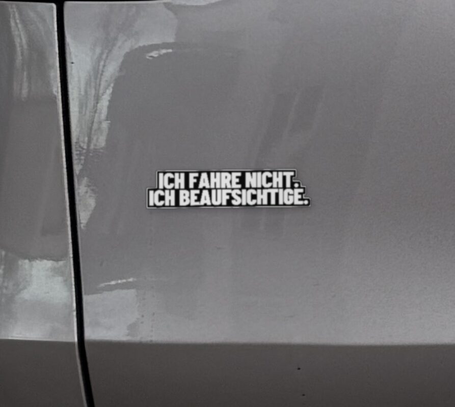 Sticker „Ich fahre nicht. Ich beaufsichtige.“ links auf der Heckklappe eines Model Y Juniper, neben dem Rücklicht