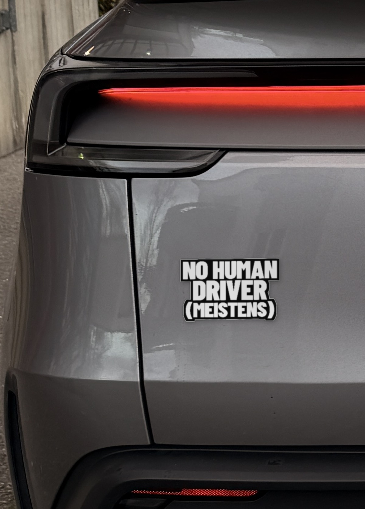 Sticker „No human driver (meistens)“ links auf der Heckklappe eines Model Y Juniper, neben dem Rücklicht